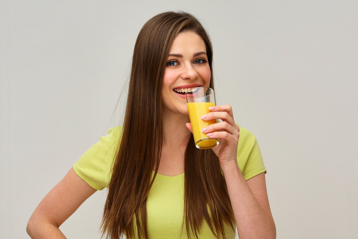 Smiling,Woman,Holding,Glass,With,Orange,Juice.,Isolated,Studio,Portrait